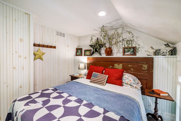 Unwind in the red queen bedroom, featuring a reclaimed-wood headboard, Pottery Barn quilt, and cozy sloped ceilings.