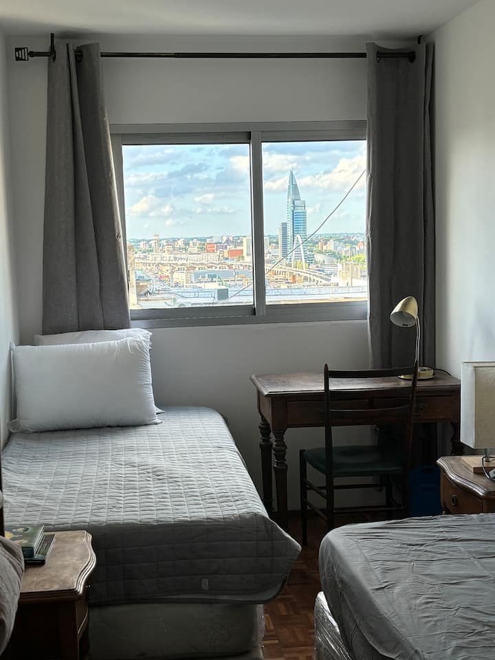 חדר עם שתי מיטות ומזרן נוסף ושולחן עבודה