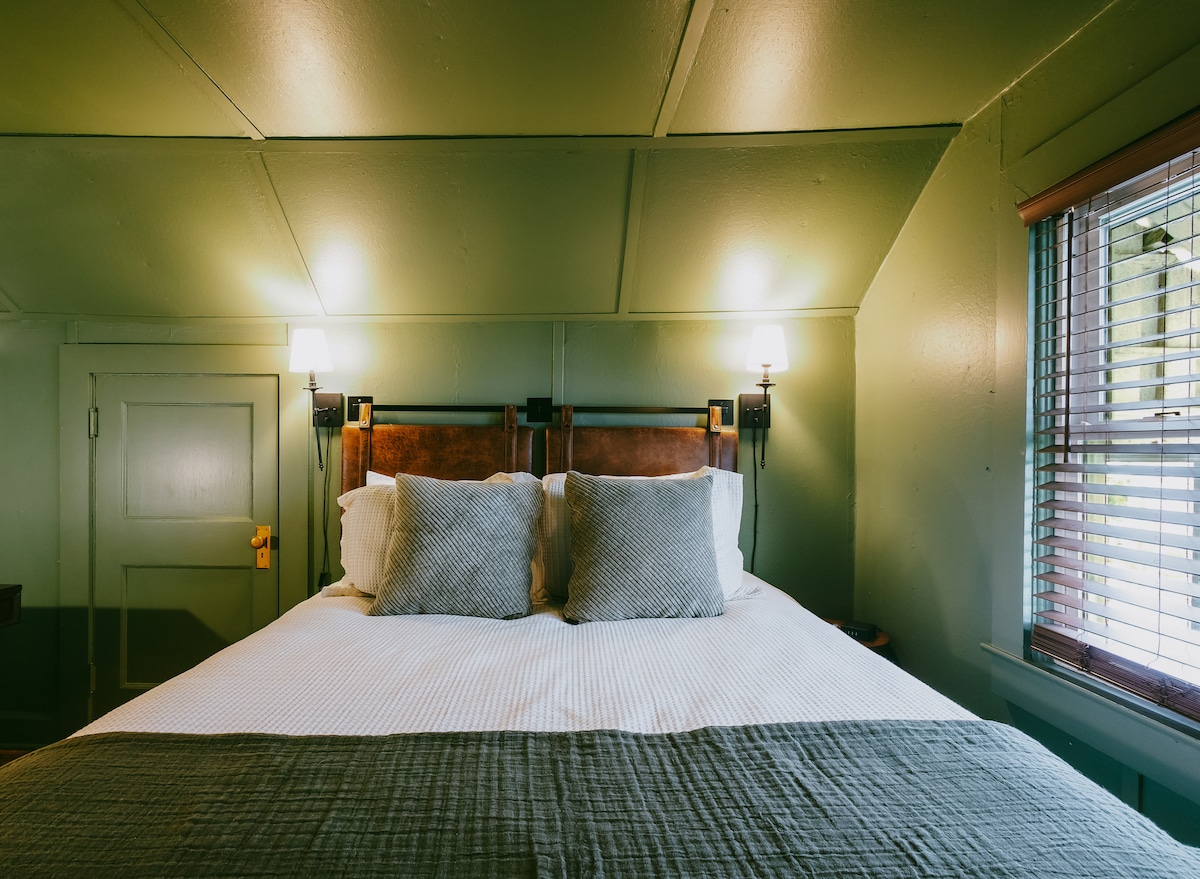The loft bedroom equipped with an adjoining half bath is a tranquil retreat inspired by the vintage doors and hardware with the modern comfort and elegance of West Elm decor.