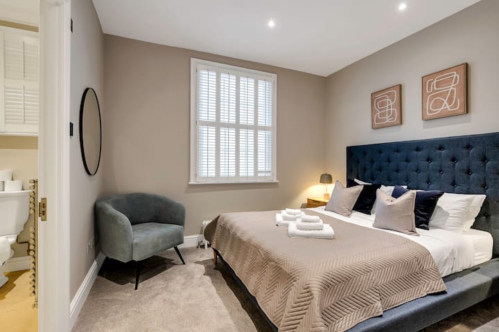 Elegante dormitorio con cabecera empotrada, ropa de cama acogedora e iluminación cálida.