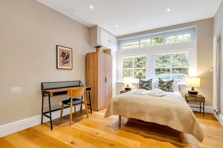 Acogedora habitación con luz natural, decoración cálida y un espacio de trabajo.