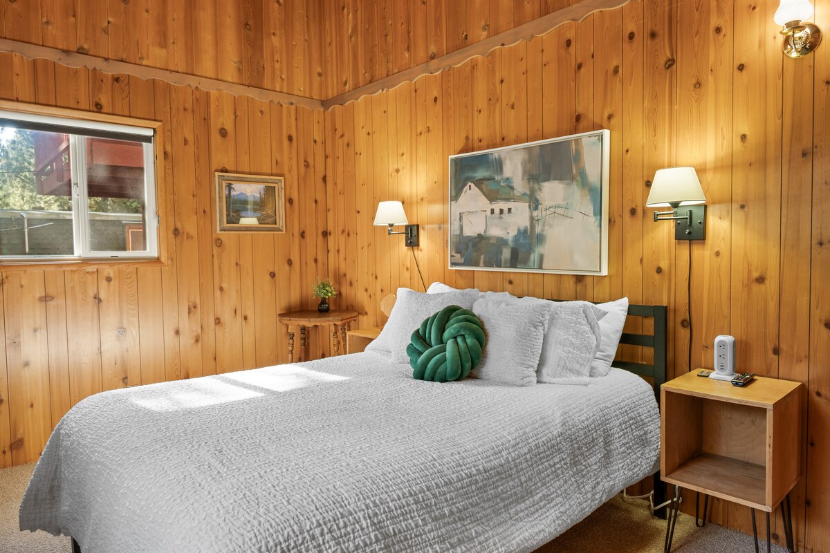 El dormitorio principal de esta cabaña es un refugio sereno, cuidadosamente diseñado para abrazar tanto la comodidad como el impresionante entorno natural. La habitación es amplia, con tablas rústicas de madera que agregan interés arquitectónico y una sensación de calidez.