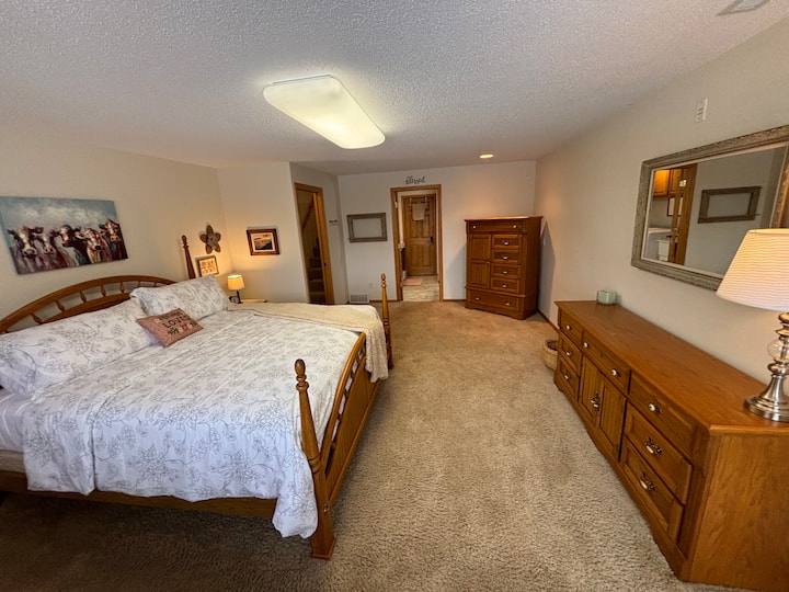 غرفة نوم واسعة في الطابق السفلي مع سرير كينج وحمام ملحق ومرافق غسيل. هناك أيضًا باب خارجي يؤدي إلى الفناء المشجر الجميل.