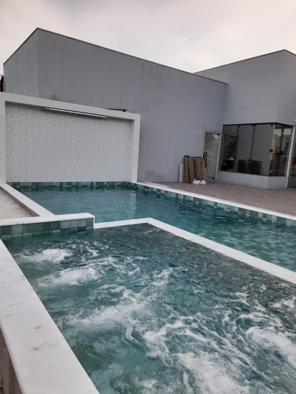 A private pool features clear turquoise water, surrounded by sleek marble edges. An adjoining jacuzzi is visible, offering a relaxing retreat. The modern architecture of the surrounding structure enhances the serene outdoor space.