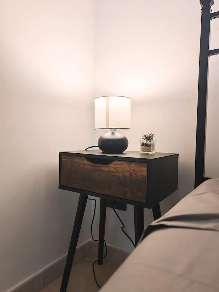 في ديكور غرفة النوم، تبرز طاولتان أنيقتان، كل منهما مجهز بغطاء مريح لإضاءة ناعمة ومريحة. تحتوي كل منضدة سرير أيضًا على درج مفيد، مثالي لتخزين الأغراض الشخصية.