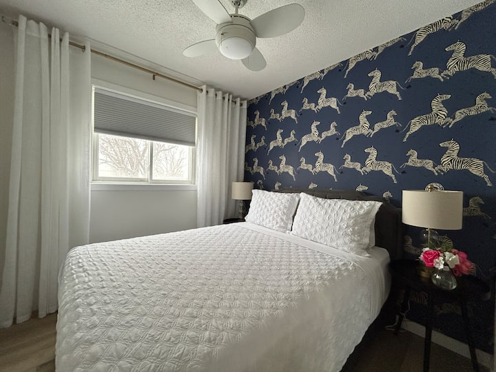 Chambre confortable au troisième étage avec un lit queen avec matelas de haute qualité, deux lampes de chevet avec prises USB, un store occultant pour un sommeil réparateur et un ventilateur de plafond.