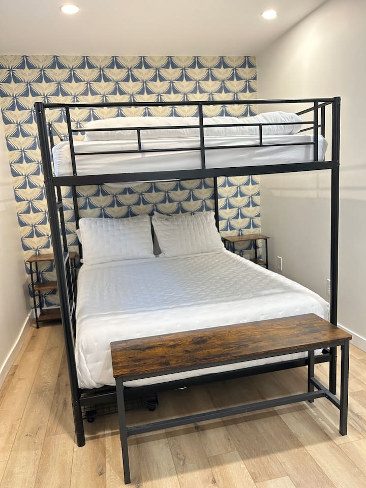 Chambre spacieuse avec lits superposés au sous-sol, dotée de deux lits doubles. Comprend des tables latérales avec prises USB pour recharger facilement les appareils.