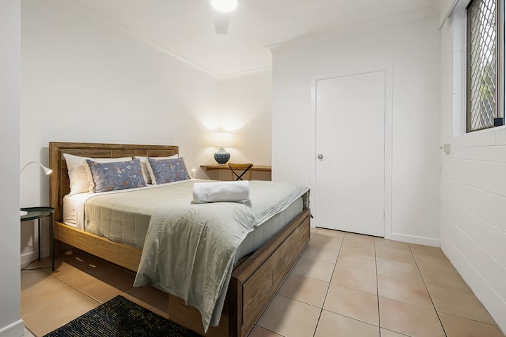 Lit queen size avec de nombreux rangements, y compris un espace suspendu et une commode. Il y a également un bureau et une chaise. 