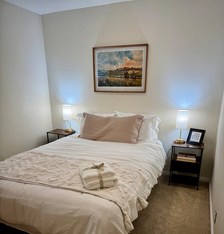 Andet soveværelse med queensize-dobbeltseng, bløde lagner og masser af puder. Hver side har et natbord med en lampe, der har indbyggede opladningsporte til enhver enhed. Dette værelse har også et vindue og et skab.