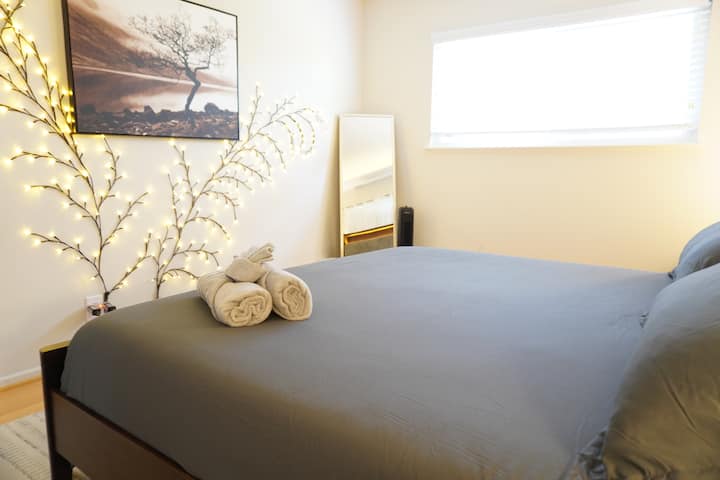 - Serene bedroom with cozy gray tones and art decor  
- Illuminated tree lights add charm and calm vibes  
- Comfortable bed with fresh linens for restful sleep  
