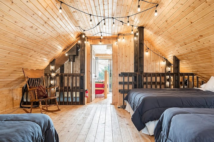 Loft bedroom area with multiple beds, vaulted ceilings, and charming cabin ambiance.