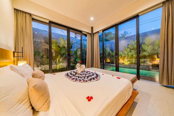A serene bedroom with direct pool access, warm lighting, and leafy views that make every stay feel calm and intimate ✨