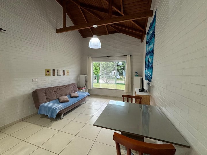 غرفة معيشة واسعة ومتكاملة مجهزة بسرير أريكة وتكييف هواء وتعتيم ستارة وتلفزيون ذكي مع تيارات وواي فاي وطاولة مع كرسيين.