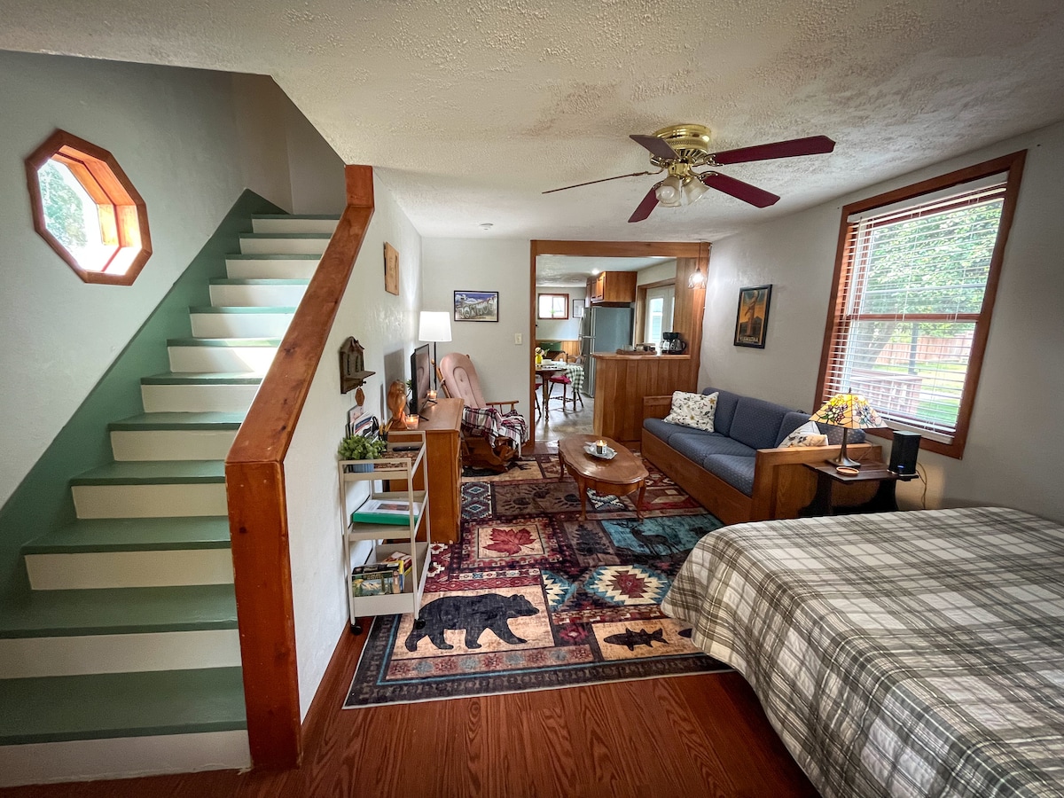 Obývacia izba v štýle štúdia má manželskú posteľ, televízor, gauč a hojdacie kreslo. 