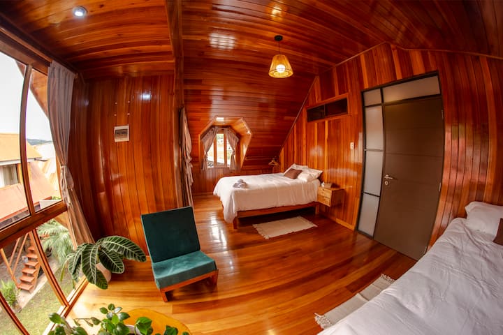 Amplia habitación doble de madera, ubicada en el segundo nivel y vista al jardín interior.
Cuenta con dos camas matrimoniales, sillones, mesa de centro y guardaropa.
