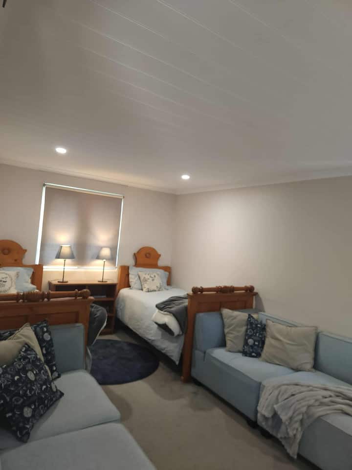 Three single beds, plus two comfy couches, a desk, books, blankets and plush pillows make a cosy kids room.