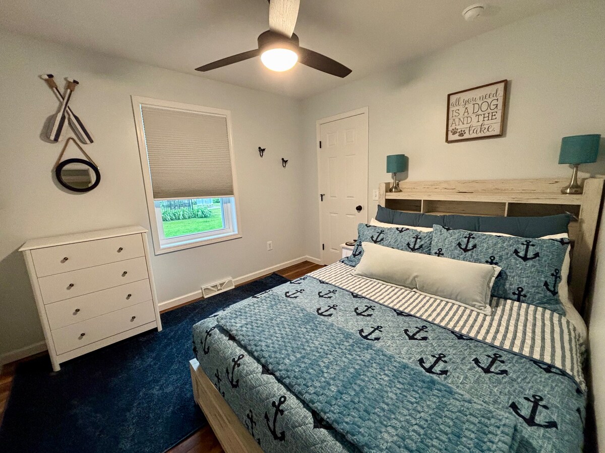 Dormitorio con cama tamaño queen y vestidor. El dormitorio tiene ventilador con control remoto con luz y TV inteligente (control remoto separado). También tiene un armario y una mesa plegable de 36" (oculta a la izquierda, silla de escritorio en el armario). El armazón de la cama tiene estantes de almacenamiento y cajones extraíbles debajo.