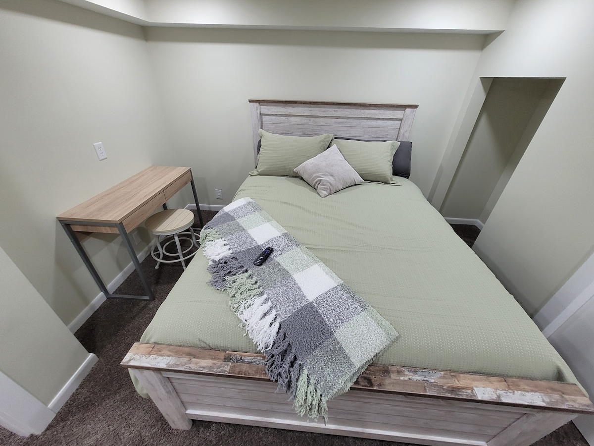 Сутеренна спалня №1 Телевизор с двойно легло с дистанционно управление, бюро с плъгин и кът за сядане и килер със закачалки.