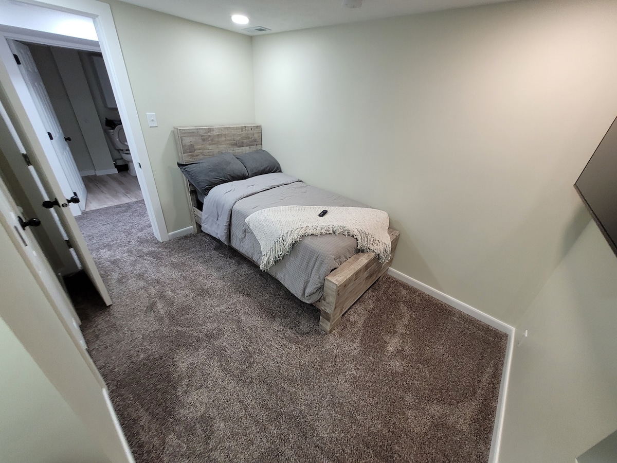 Сутеренна спалня №3. Изходен прозорец, единично легло, единично сгъваемо легло в килера, телевизор с дистанционно управление, скрин и килер със закачалки.