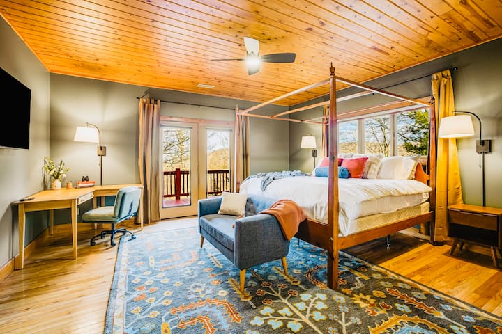 Spacious primary suite with a king canopy bed, private balcony, and a cozy workspace—perfect for relaxing or getting things done