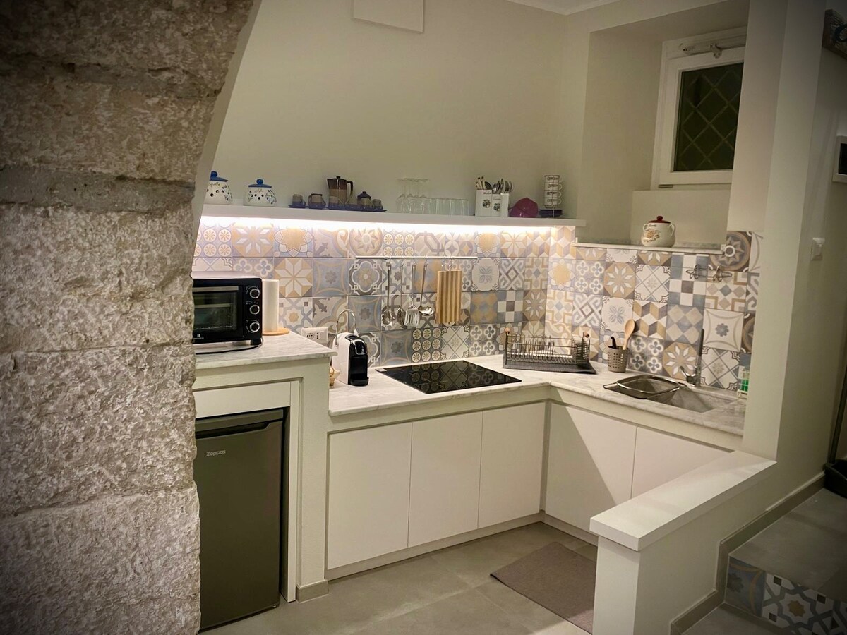 A modern kitchen features patterned tile backsplash and sleek cabinetry. Essential appliances, including a microwave and compact refrigerator, are present. A coffee maker rests on the countertop, alongside utensils and dishware. Soft lighting enhances the space, creating a functional and inviting cooking environment.