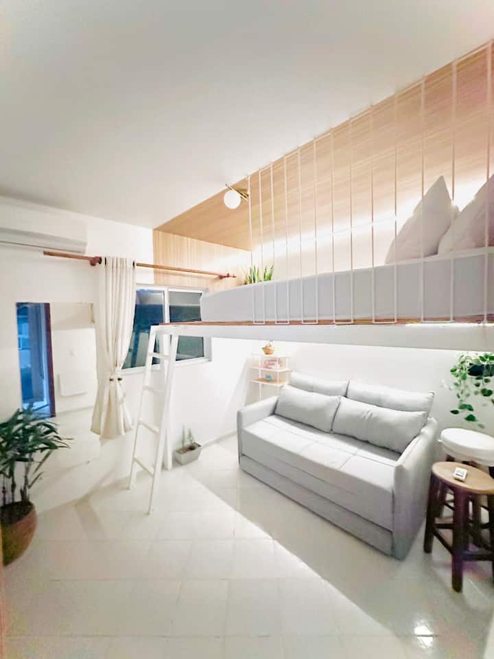 Habitación con cama suspendida estilo loft con aire acondicionado y sofá cama.
