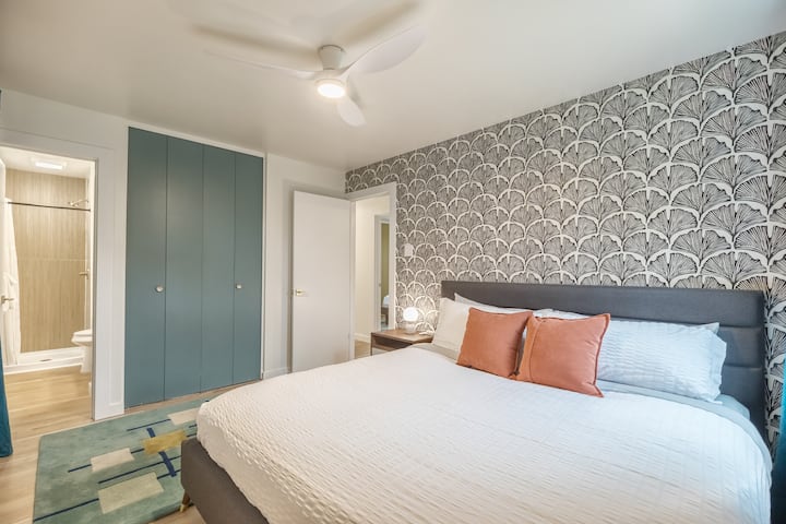 Una cómoda suite tamaño king con texturas cálidas, decoración moderna e iluminación suave, diseñada para ayudarlo a instalarse y disfrutar de una noche de sueño reparador.