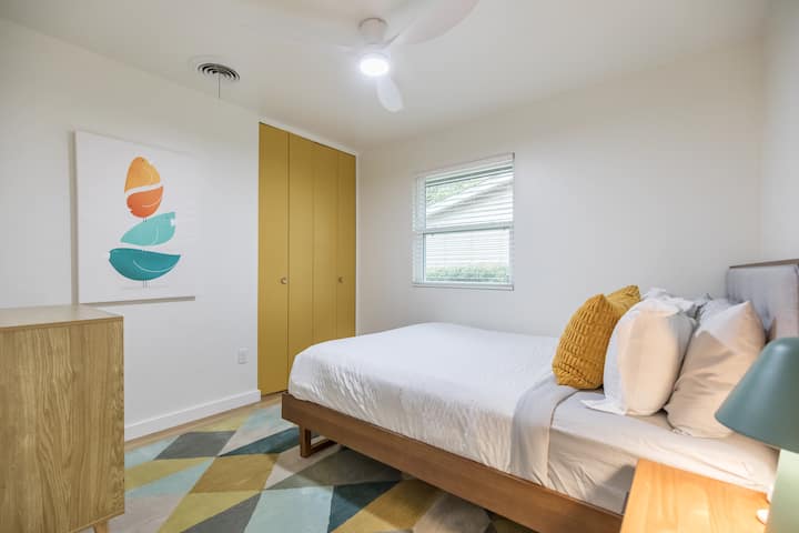 Una habitación luminosa con puertas de armario color mostaza, una cómoda cama tamaño queen y una decoración de estilo moderno: un espacio sencillo y alegre para una gran noche de sueño.