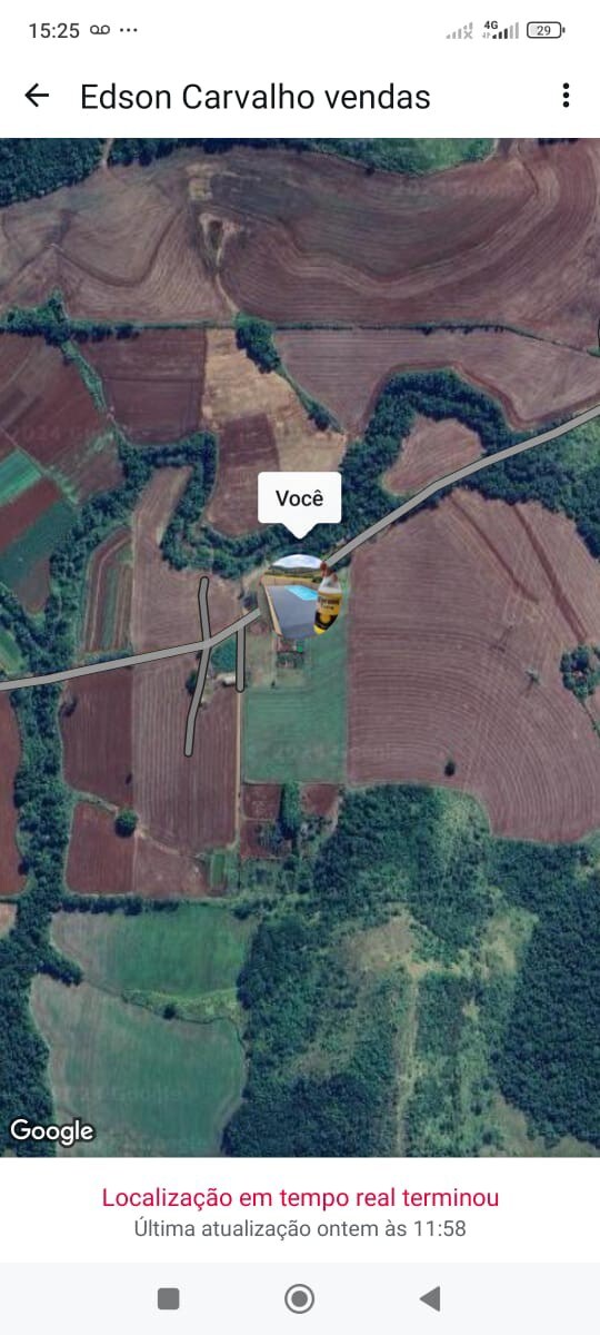 An aerial view captures the expansive green landscape surrounding the property. Nearby roads are visible, winding through fields that exhibit various shades of brown and green, showcasing agricultural land. This tranquil setting emphasizes the rural surroundings, with no neighboring properties in sight.