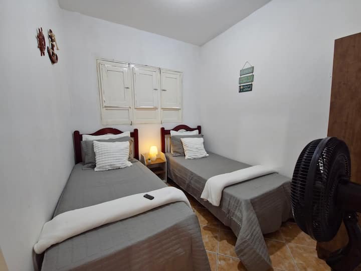 Ოთახი 1, საწოლის დეტალებით, უკანა ტანსაცმლითა და ფეხის ვენტილატორით (დისტანციური მართვის პულტით).