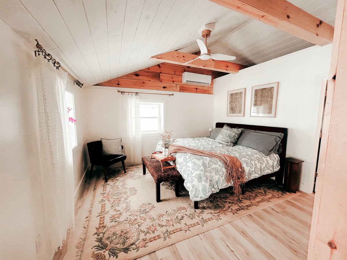 Luxe kingsize bed met gewelfde plafonds, plafondventilator met afstandsbediening, uitzicht op het meer en een volledige ontspanningssfeer. 