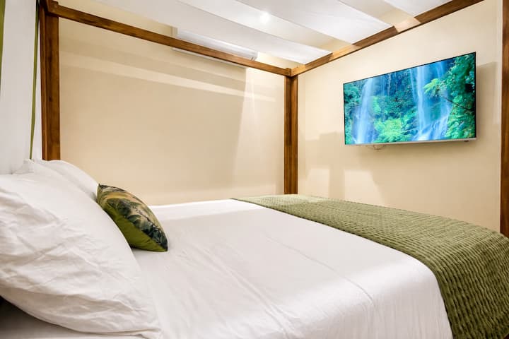Dormez sous les tropiques ! Lit à baldaquin, déco végétale et TV écran plat pour des soirées relaxantes et un réveil en douceur dans un cocon nature.