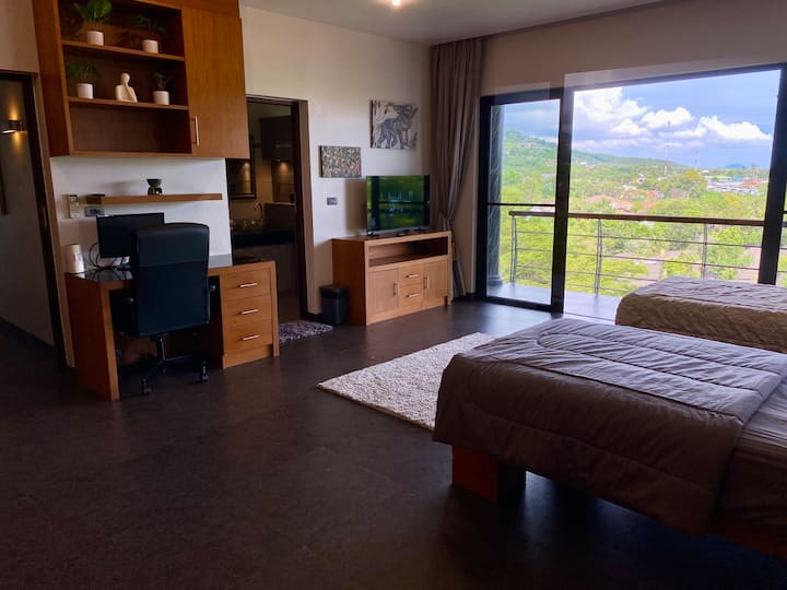 غرفة نوم كبيرة بمساحة 30 مترًا مربعًا مع أثاث وسريرين مزدوجين وتلفزيون ذكي ومروحة سقف ومكيف هواء ومكتب عمل وبيانو. 