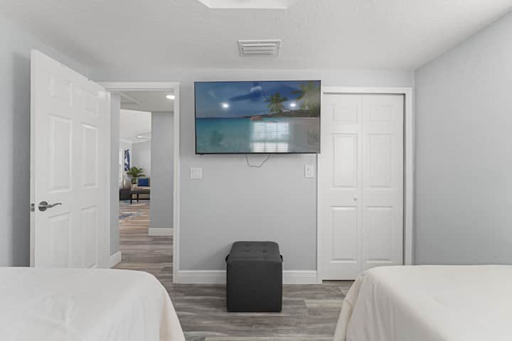 Twin bedroom with a wall-mounted TV and a simple, comfortable setup for guests.