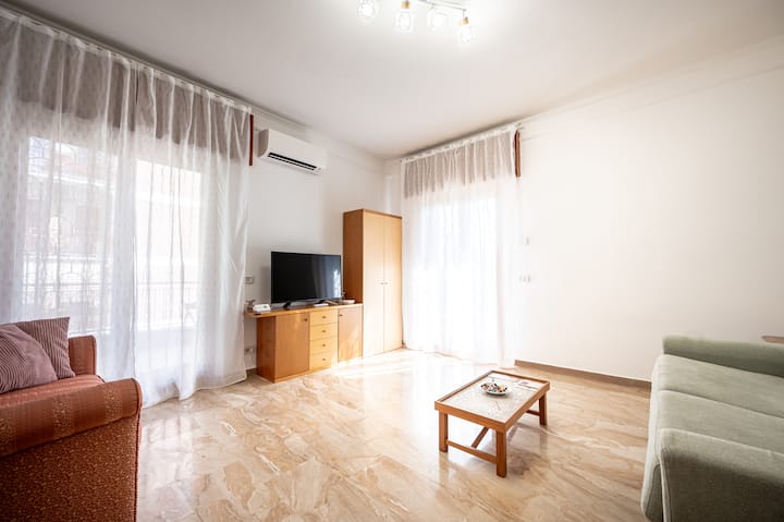 Ampio soggiorno con aria condizionata e riscaldamento a termosifoni, armadio, cassettiera, divano letto alla francese e singolo, tavolini a mosaico, comodino, Smart TV, tende oscuranti, tapparelle elettriche e zanzariere. Doppio accesso al terrazzo.