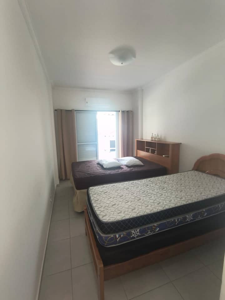 חדר שינה עם שתי מיטות, אחת זוגית ואחת יחיד, ומיזוג אוויר לנוחות רבה יותר.