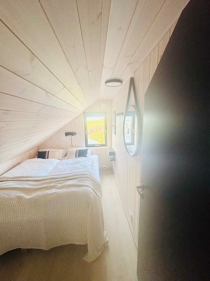 חדר שינה ליד הסלון בלופט עם תקרות משופעות מקסימות, אווירה נעימה ורמקול ארון ספרים חכם עם מטען אלחוטי 