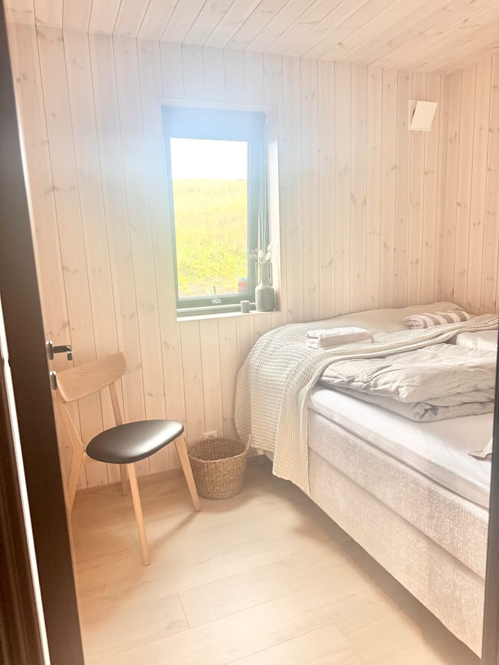 חדר שינה עם מיטה זוגית נוחה, מזרנים איכותיים ונופים לכיוון החלק האחורי השקט.