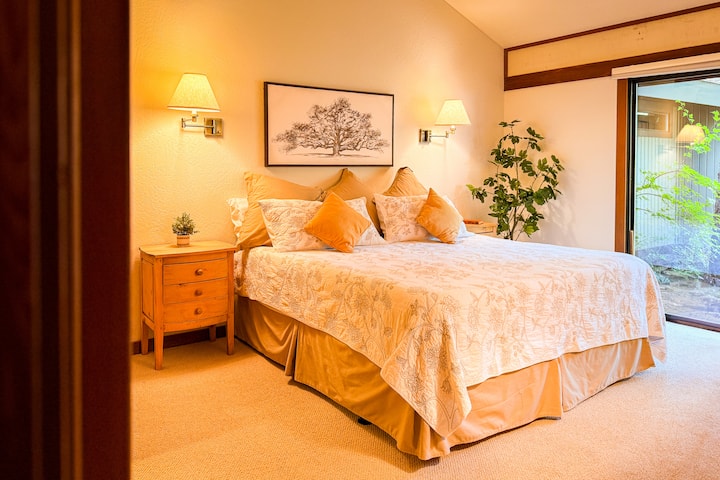 Peaceful master bedroom featuring a plush king bed, soft lighting, and cozy decor.  Sliding glass doors open to the backyard, creating a relaxing retreat perfect for restful nights and slow mornings.