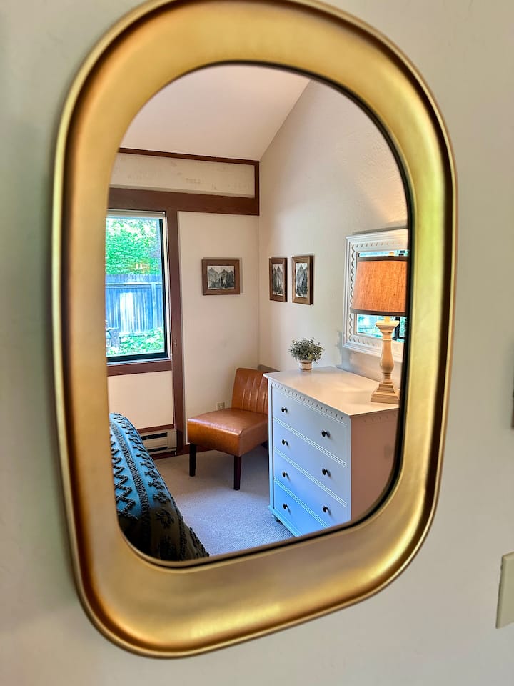 A charming glimpse of the second bedroom, captured through the mirror - showcasing cozy details, natural light, and a peaceful retreat for guests.