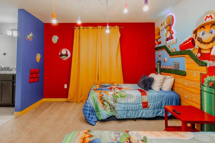 This children's room is a vibrant haven with bright red and blue walls and whimsical character murals. Two cozy beds with themed bedding create a fun and imaginative sleeping space for young guests to enjoy.