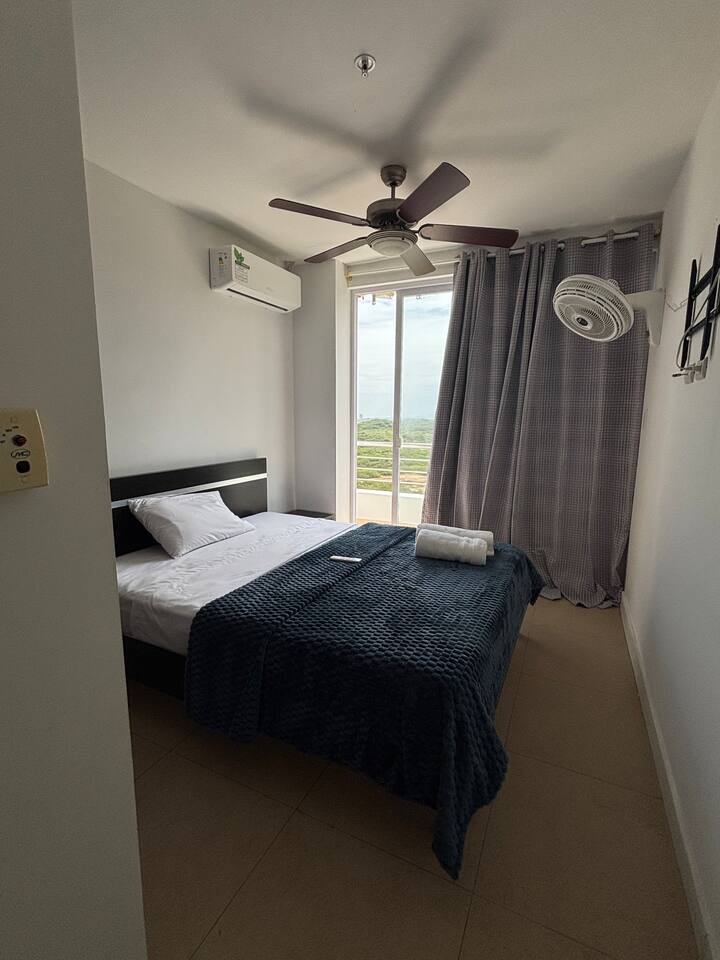 Chambre avec placard, climatisation et balcon. Elle dispose également d'un ventilateur