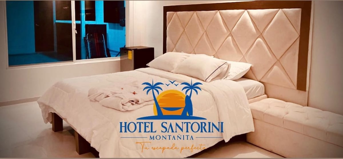 A spacious sleeping area is presented with a plush, light-colored bed featuring a stylish tufted headboard. Natural light floods the room through large windows, illuminating the simple decor. A cozy bench is available at the foot of the bed for added convenience.