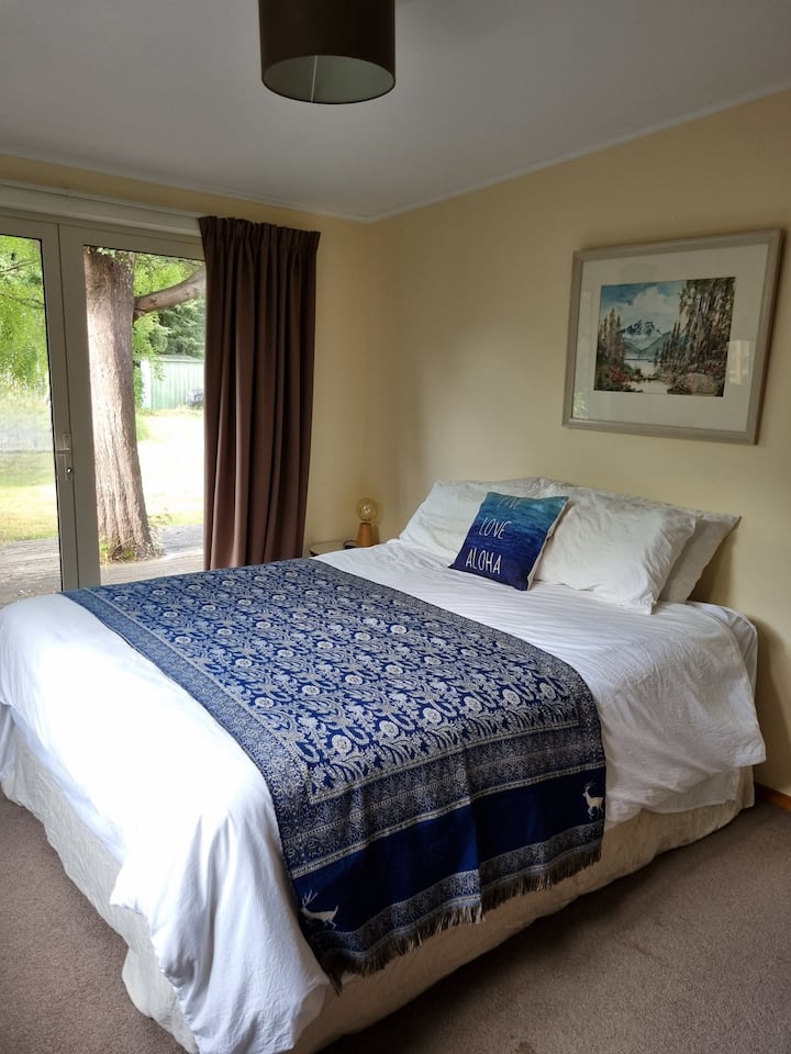 בחדר השינה הזה יש שידת מגירות לאחסון ודלתות צרפתיות שנפתחות למרפסת האחורית. 