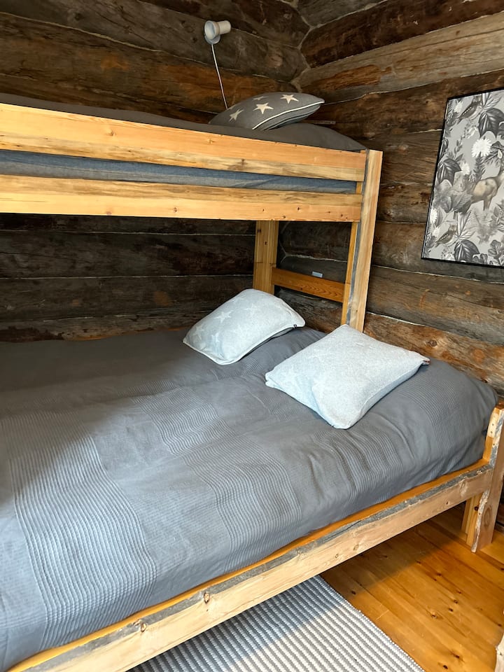 Cette chambre peut accueillir cinq personnes si nécessaire. Une fenêtre donne sur une paisible route de cottage. 