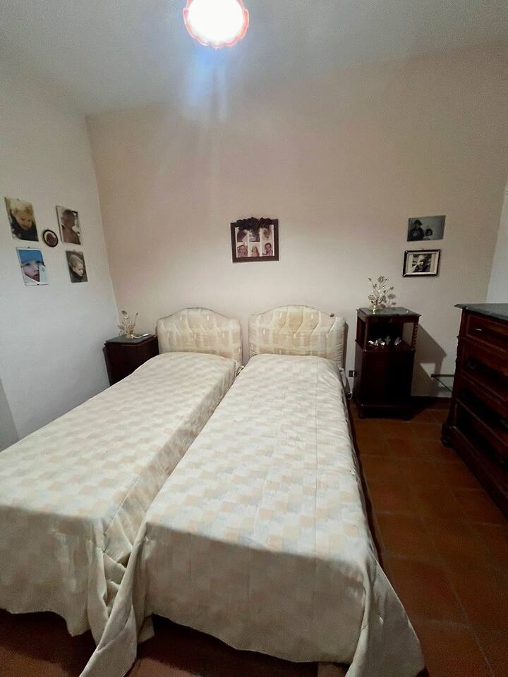 Segundo dormitorio con dos camas individuales y cabecero tapizado. Con un solo colchón y funda de colchón. Lámpara de mesa y cómoda con tres cajones grandes, un cajón más estrecho y espejo 