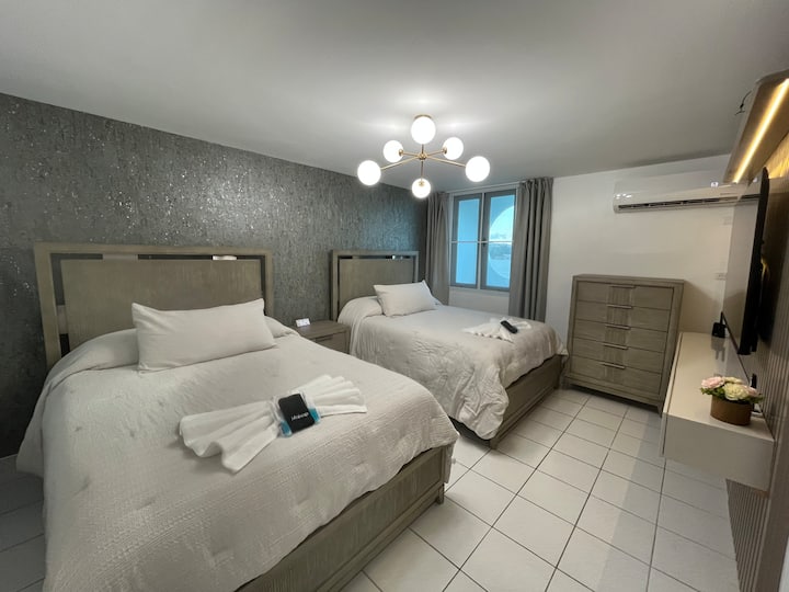 Chumba cha kulala kilicho na vitanda viwili vya Queen, meza ya usiku, hifadhi ya nguo, kabati, ufikiaji wa bafu, televisheni ya "65" na kiyoyozi. 