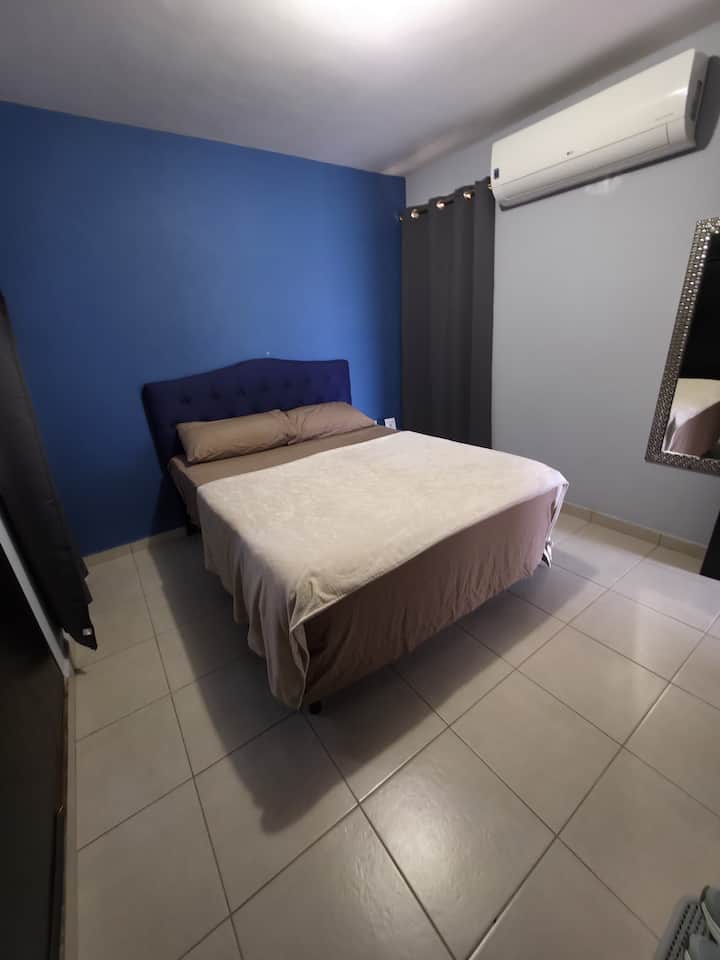 Spavaća soba s bračnim krevetom, klima-uređajem i pametnim televizorom.