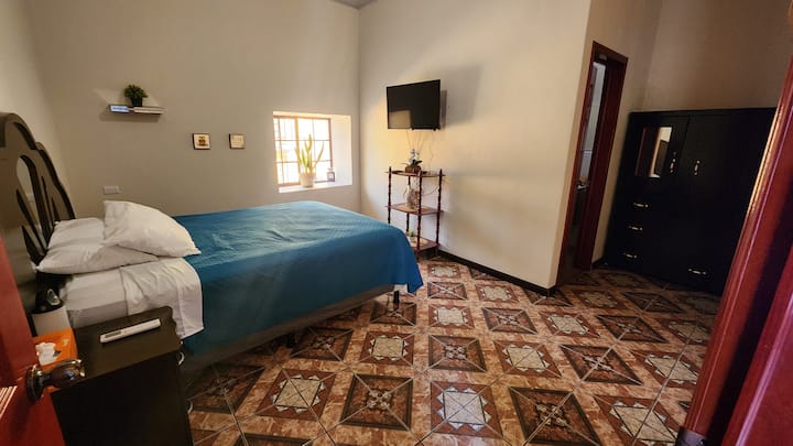 Chumba cha kulala chenye nafasi kubwa na kitanda aina ya Queen na sofa.