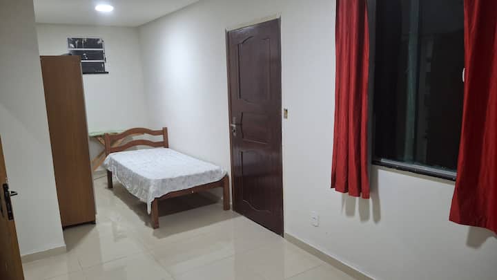 غرفة نوم في الطابق الأرضي مع سرير أريكة مزدوج وسرير فردي ومروحة وحمام اجتماعي قريب